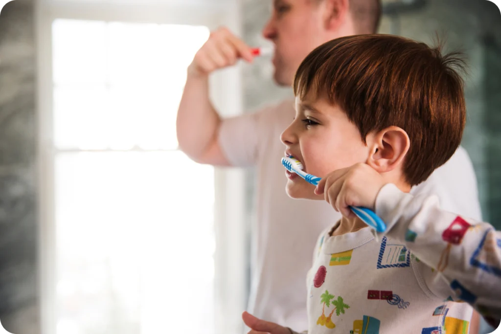 Jeune enfant se brossant les dents devant le miroir