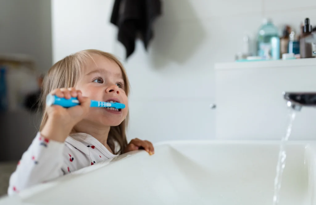 Fillette se brossant les dents au-dessus du lavabo