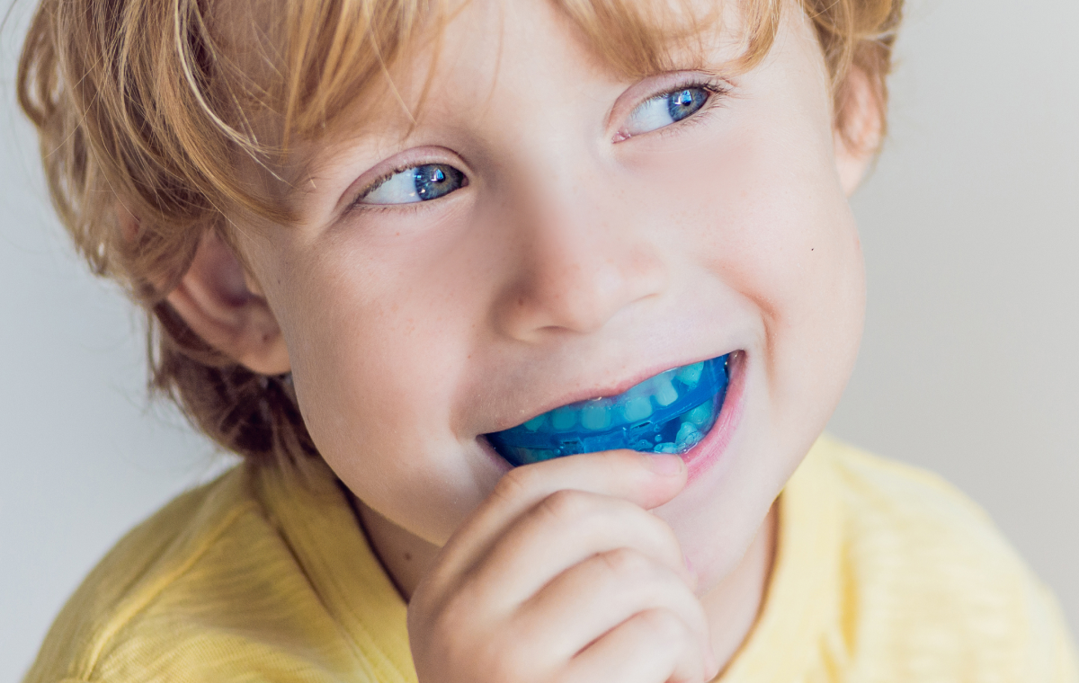 Garçon plaçant un éducateur fonctionnel bleu entre ses dents